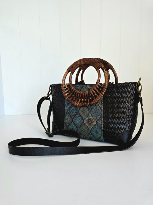 Woven handbag with a decorative rattan handle on a white background
