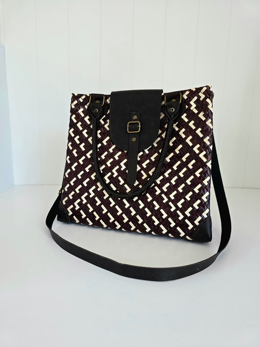 Brown and white woven handbag with a strap on a white background