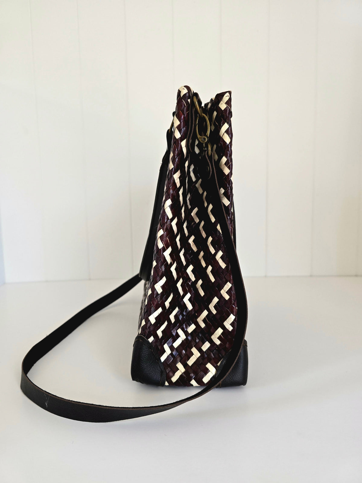 Brown and white patterned bag with a strap on a white background