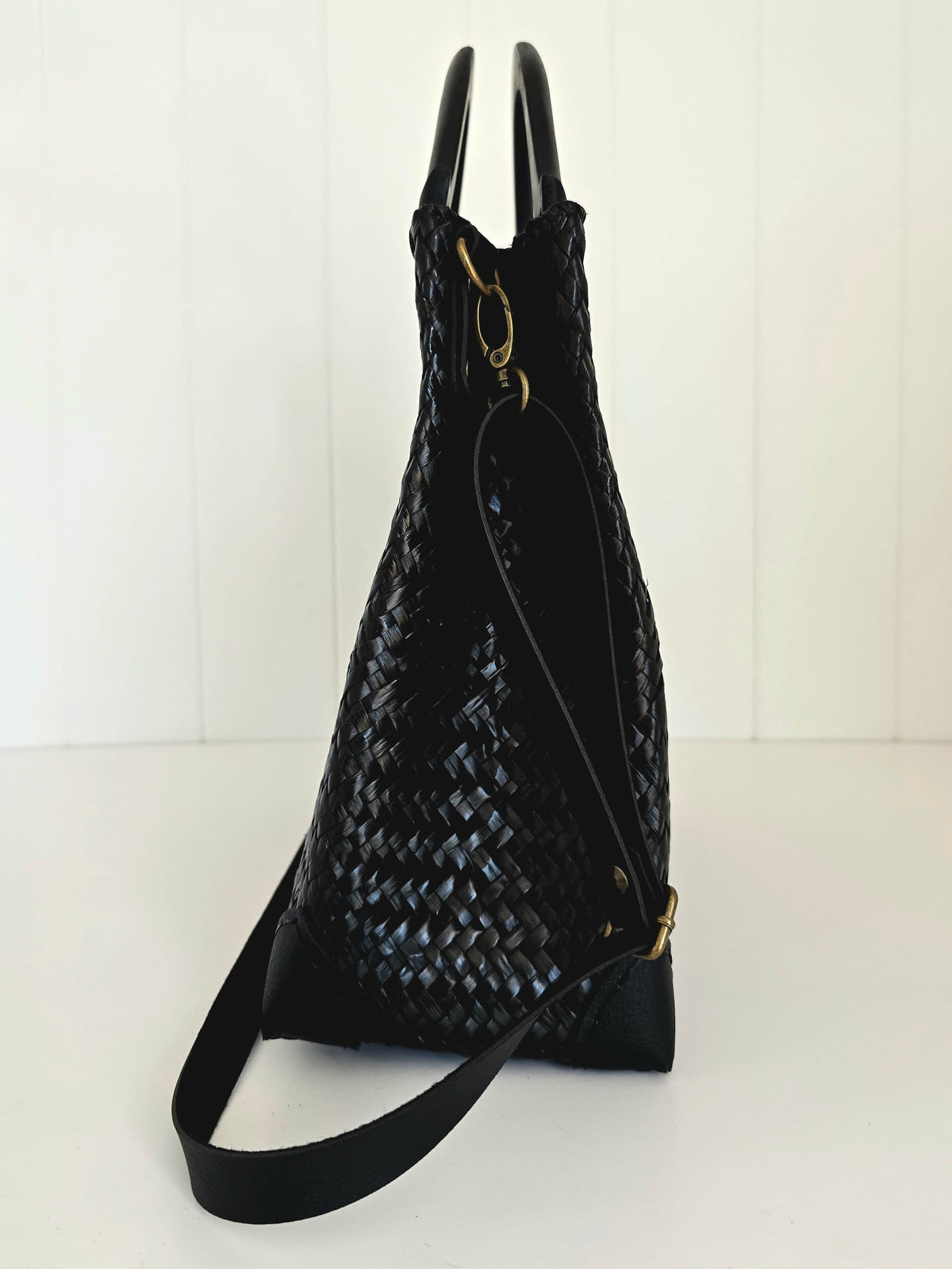 Black woven handbag with a strap on a white background