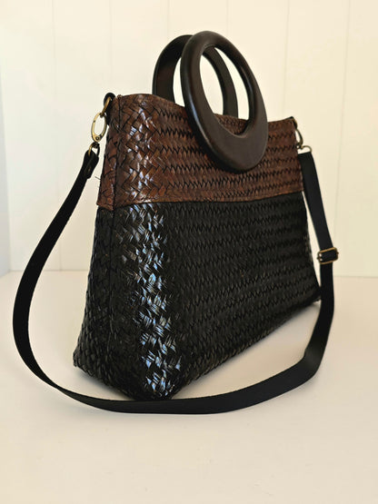Brown and black woven handbag with a handle on a white background
