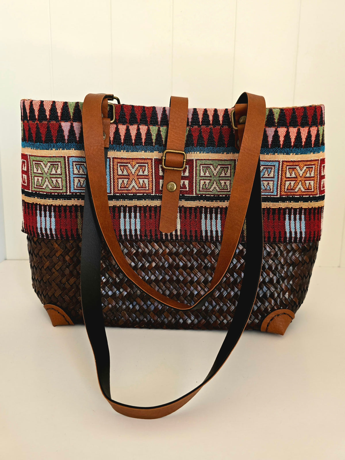 Hand woven Patterned handbag with brown straps on a white background