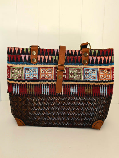 Hand woven Handbag with aztec fabric panel around top.  Faux leather handles and strap to close bag 