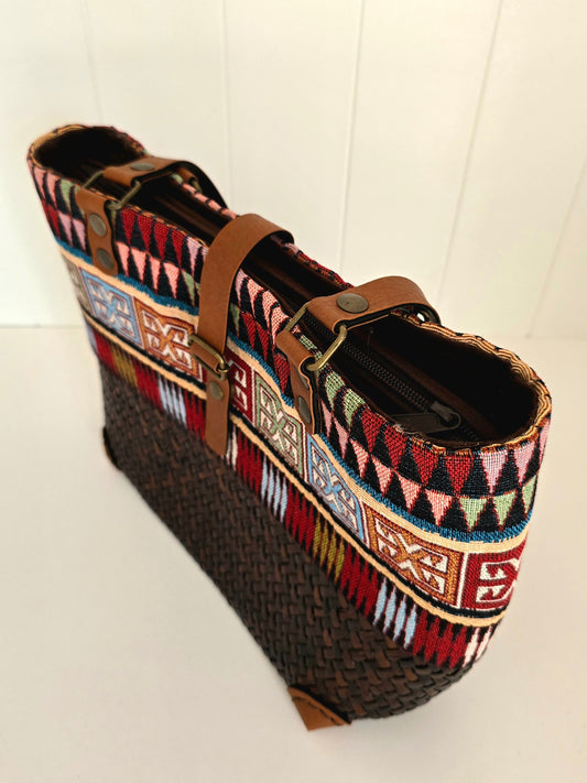 Multicolored patterned bag with brown strap on a white background