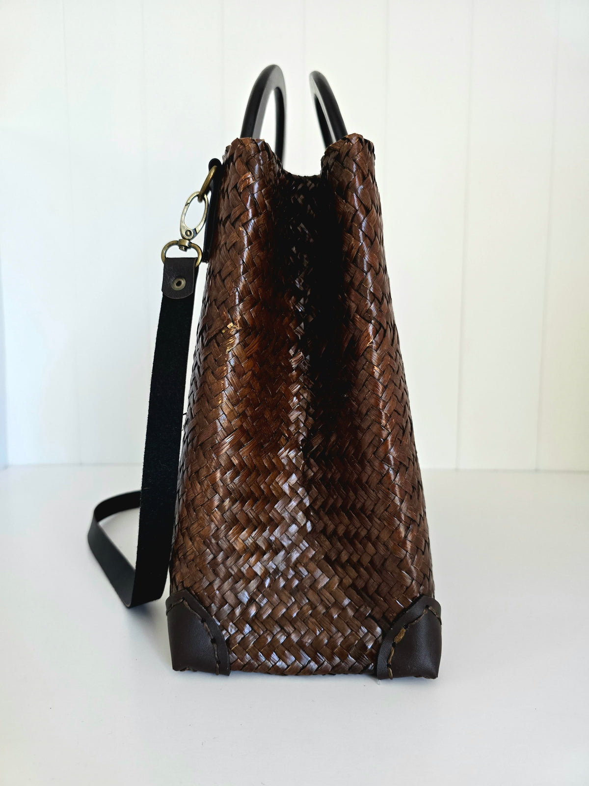 Brown woven handbag with black accents on a white background