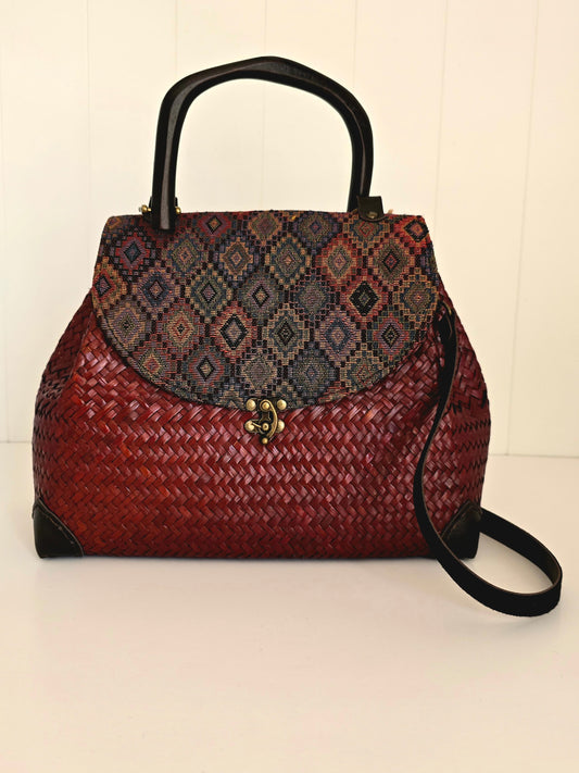 Woven handbag with patterned flap on a white background