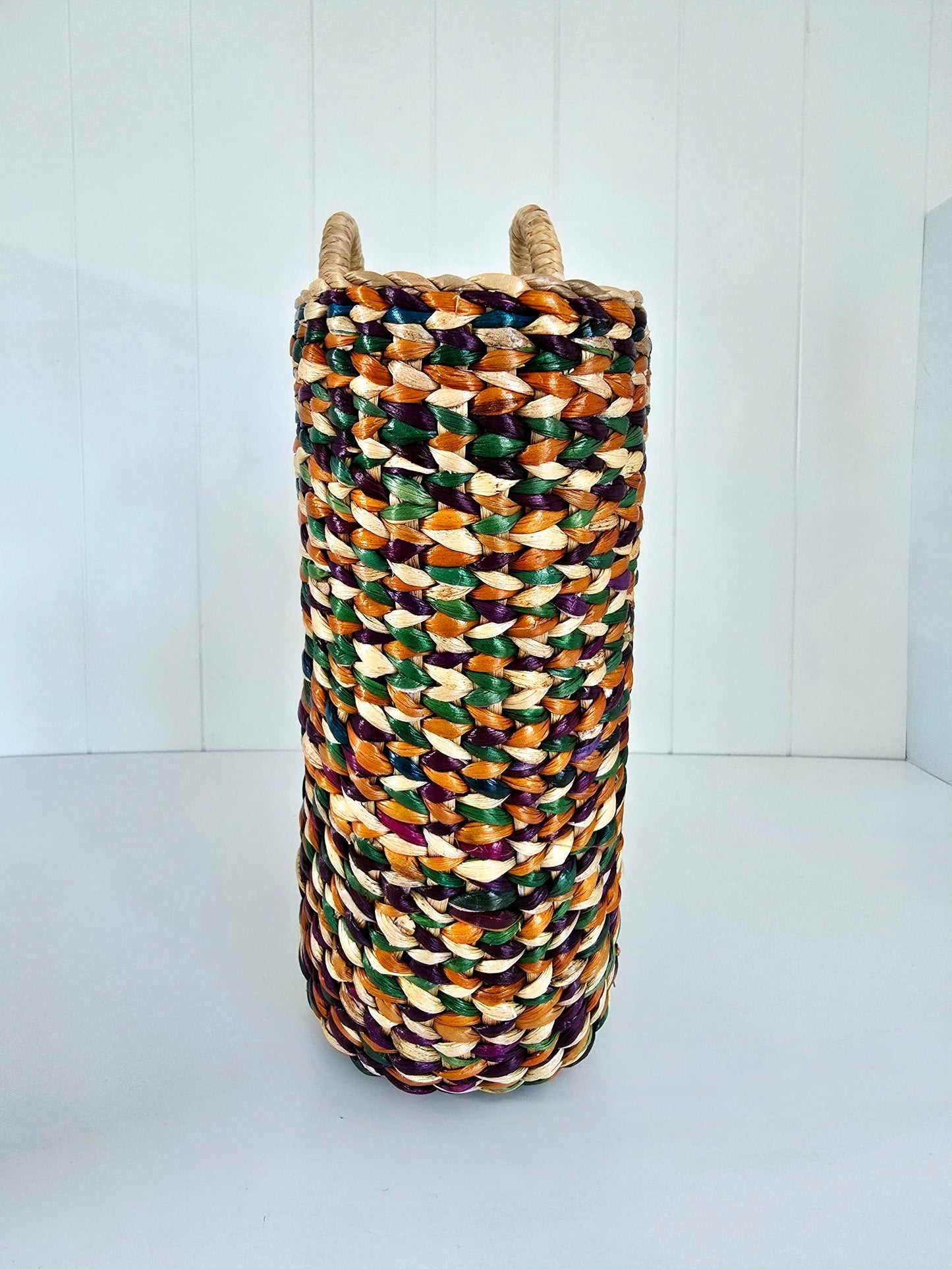 Multicolored woven basket on a white background looking at it from one end