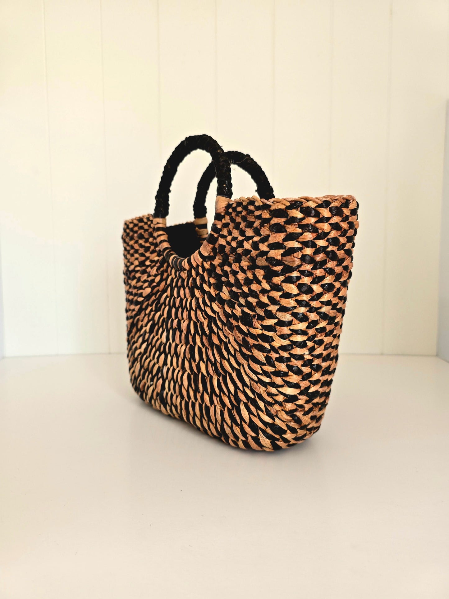Woven bag with black handles on a light background
