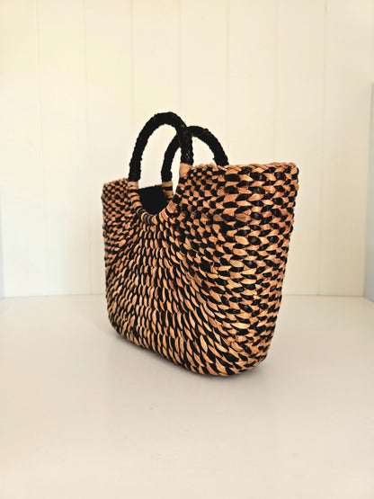 Woven bag with black handles on a light background