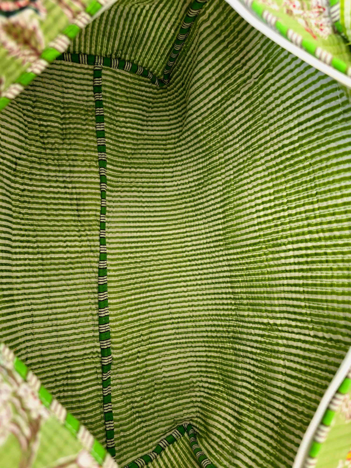 Close-up of the inside of a green woven bag with a floral patterned background