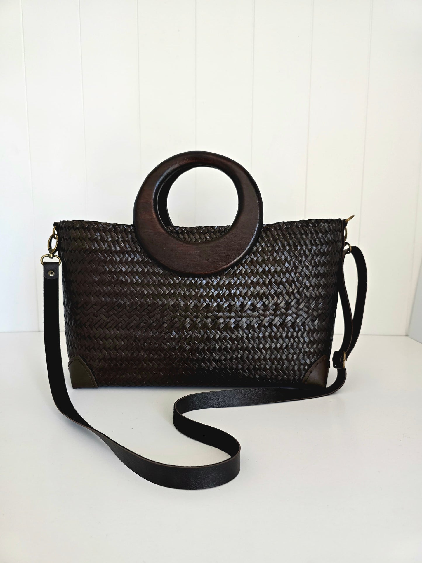 Black woven handbag with wooden handle on a white background