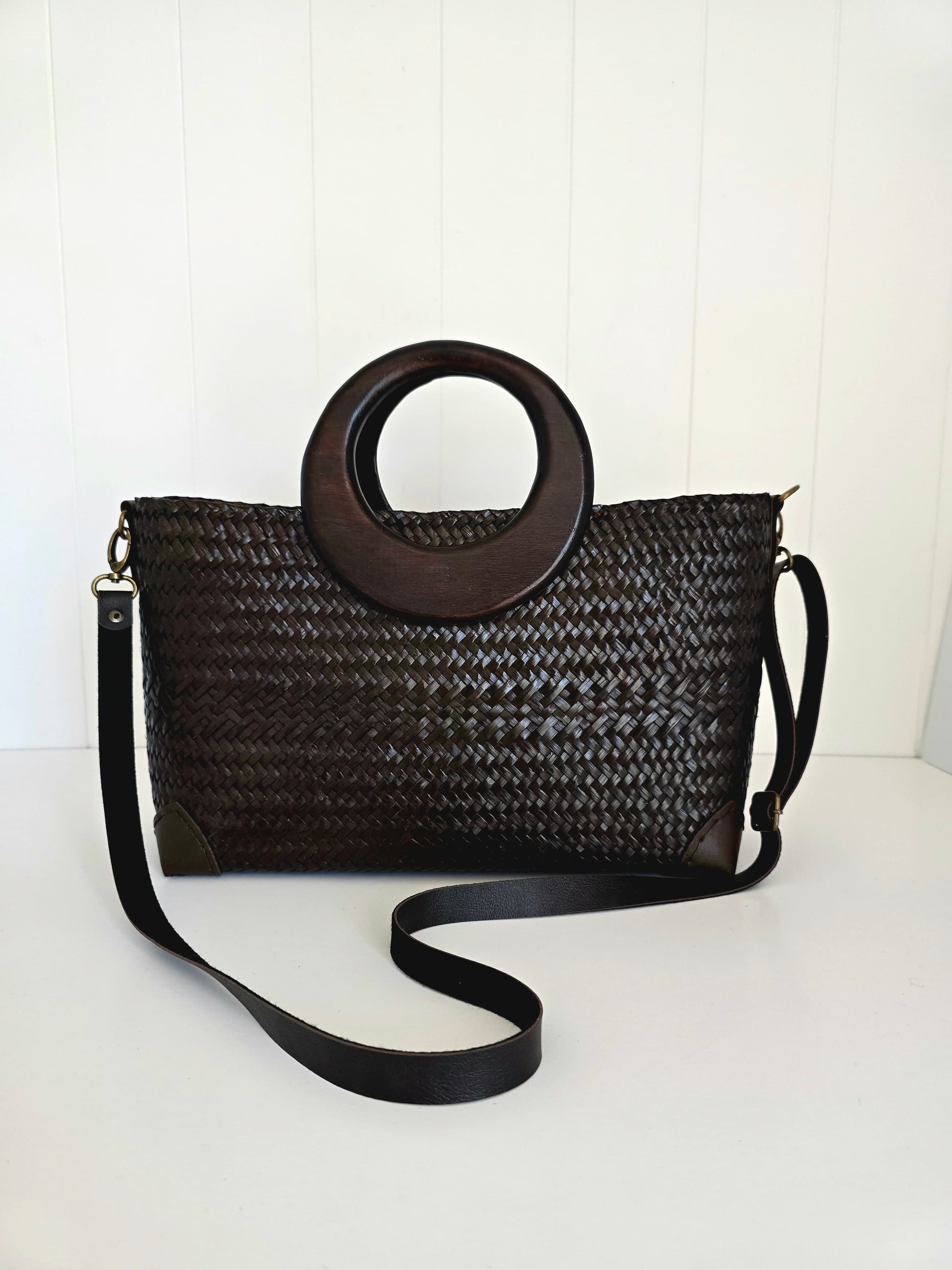 Black woven handbag with wooden handle on a white background