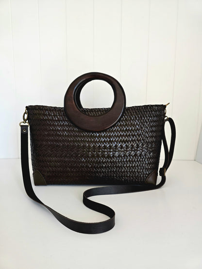 Black woven handbag with wooden handle on a white background