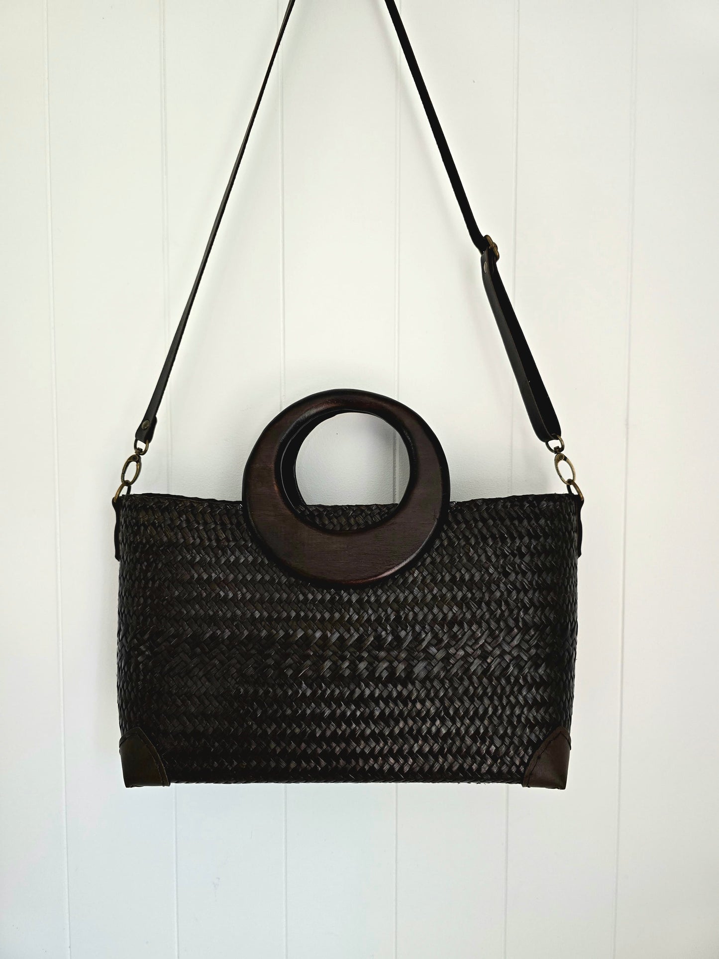 Black woven handbag with wooden ring handle on a white background